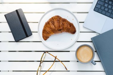 Kafedeki bir masada bir fincan sade kahveyle yeni pişmiş kruvasan..