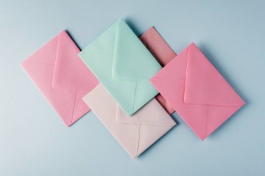 Açık mavi arkaplanda pastel renkli zarfların koleksiyonu.