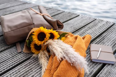 Gezginin sırt çantası, günlük ve bir demet ayçiçeği rıhtımda yatıyor..