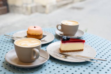Kaldırımdaki kafede masada iki fincan kapuçino ve tatlılar..