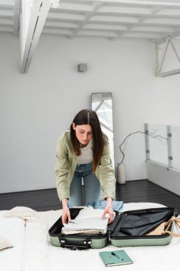 Genç esmer kadın yurtdışına solo seyahat için bavul hazırlıyor. Yaz tatili. Deniz aşırı seyahat..