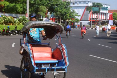 Semarang, Indonesia - May 21, 2023 : A man brings a Becak which is a means of transportation at Simpang Lima, Semarang city clipart