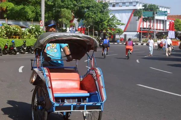 Semarang, Endonezya - 21 Mayıs 2023: Bir adam Simpang Lima, Semarang şehrine ulaşım aracı olarak bir Becak getiriyor