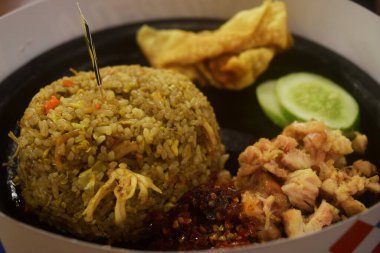 Kızarmış pilav, dilimlenmiş tavuk ve kırmızı biber sosu bir restorandaki ahşap masada servis edilir.