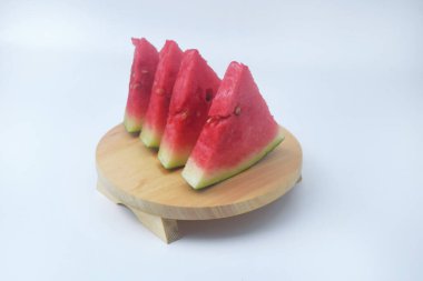 Kırmızı karpuz dilimleri ahşap bir zeminde ve izole edilmiş beyaz arka plandadır.