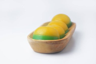 Yuvarlak, sarı ve yeşil katmanlı bir kekin, geleneksel Endonezya yemeği olan ahşap bir kasede yakın plan fotoğrafını çek.