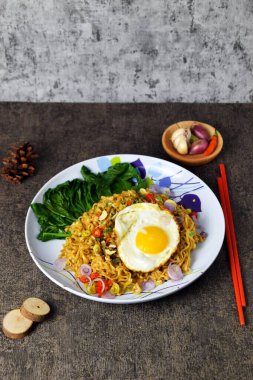 Yumurta ve çimento kaplı bir tabakta karışık sebzeli kızarmış erişte.