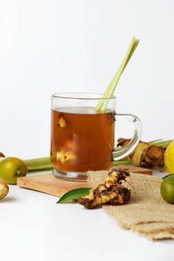 Kırmızı zencefilli sıcak bir bardakta, zencefil, limon, sıkılmış portakal, taze soğan ve beyaz izole edilmiş arka planla çekilmiş yakın çekim fotoğrafı. Sağlıklı içecekler tedavi için kullanılabilir.