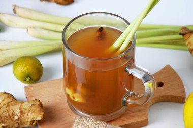 Kırmızı zencefilli sıcak bir bardakta, zencefil, limon, sıkılmış portakal, taze soğan ve beyaz izole edilmiş arka planla çekilmiş yakın çekim fotoğrafı. Sağlıklı içecekler tedavi için kullanılabilir.