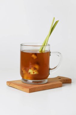 Ateşli kızıl zencefilin yakın plan fotoğrafı. Bardakta, tahta bardakta ve izole edilmiş beyaz arka planda. Sağlıklı içecekler tedavi için kullanılabilir.