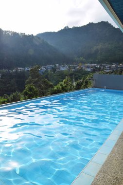 The atmosphere of the swimming pool of a villa. View with a pine forest background clipart