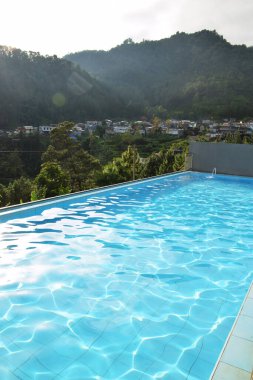 The atmosphere of the swimming pool of a villa. View with a pine forest background clipart