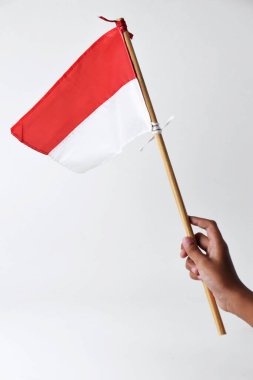Bir çocuğun eli Endonezya ulusunun kırmızı ve beyaz bayrağını tutuyor ve sallıyor.