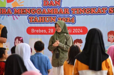 Tegal, Endonezya - 28 Temmuz 2024: Bir sunucu çocukları Brebes, Central Java, Endonezya 'daki kütüphane salonuna jimnastik yapmaya davet ediyor. Birlikte çalışmadan önce daha rahat olmak için egzersiz yapılır.