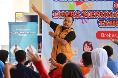 Tegal, Endonezya - 28 Temmuz 2024: Bir sunucu çocukları Brebes, Central Java, Endonezya 'daki kütüphane salonuna jimnastik yapmaya davet ediyor. Birlikte çalışmadan önce daha rahat olmak için egzersiz yapılır.