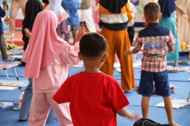 Tegal, Indonesia - July 28, 2024 : A presenter invites children to do gymnastics in the library office hall in Brebes, Central Java, Indonesia. Exercise is done to be more relaxed before doing the co clipart