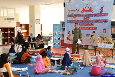 Tegal, Indonesia - July 28, 2024 : A presenter invites children to do gymnastics in the library office hall in Brebes, Central Java, Indonesia. Exercise is done to be more relaxed before doing the co clipart