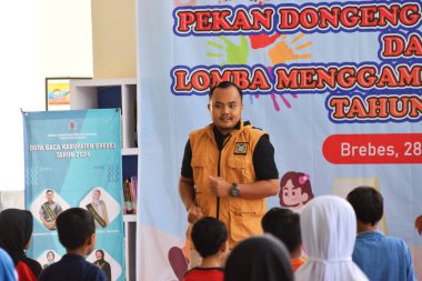 Tegal, Endonezya - 28 Temmuz 2024: Bir sunucu çocukları Brebes, Central Java, Endonezya 'daki kütüphane salonuna jimnastik yapmaya davet ediyor. Birlikte çalışmadan önce daha rahat olmak için egzersiz yapılır.