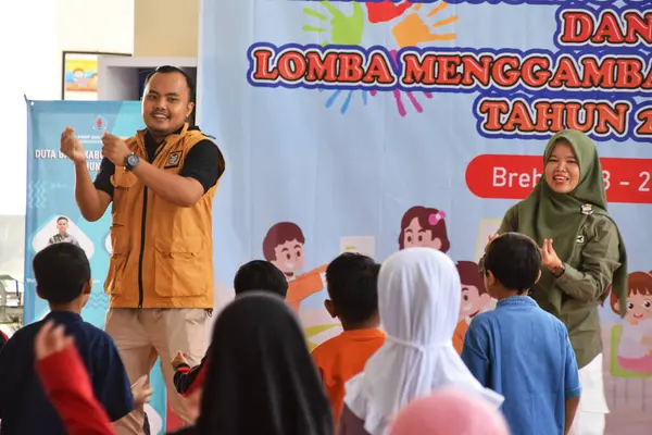 Tegal, Endonezya - 28 Temmuz 2024: Bir sunucu çocukları Brebes, Central Java, Endonezya 'daki kütüphane salonuna jimnastik yapmaya davet ediyor. Birlikte çalışmadan önce daha rahat olmak için egzersiz yapılır.