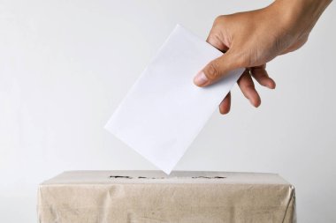 Endonezyalı bir adamın eli oy pusulasını karton bir sandığa koyuyor. Seçim konsepti. Beyaz arkaplanı izole et