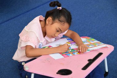 Tegal, Indonesia - July 28, 2024 : Small children from Indonesia are drawing in a painting competition at the regional library in Brebes City clipart