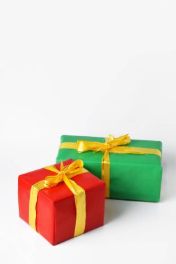 Sarı kurdeleli iki kırmızı ve yeşil hediye kutusu beyaz izole bir arka planda. Noel günü ve yeni yıl için hediye sembolü