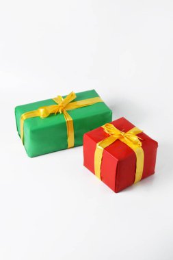 Sarı kurdeleli iki kırmızı ve yeşil hediye kutusu beyaz izole bir arka planda. Noel günü ve yeni yıl için hediye sembolü