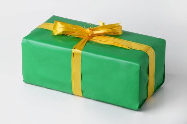 Altın sarısı kurdeleli yeşil bir hediye kutusu beyaz izole bir arka planda. Noel ve Yeni Yıl kutlamalarının sembolü