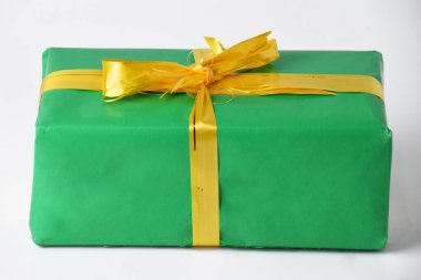 Yakından bakınca, yeşil hediye paketi beyaz izole arka planda altın sarısı kurdele. Hediye kutusu Noel ve Yeni Yıl kutlamalarının bir parçası.