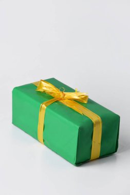 Altın sarısı kurdeleli yeşil bir hediye kutusu beyaz izole bir arka planda. Noel ve Yeni Yıl kutlamalarının sembolü