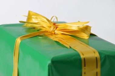Altın sarısı kurdeleli yeşil bir hediye kutusu beyaz izole bir arka planda. Noel ve Yeni Yıl kutlamalarının sembolü