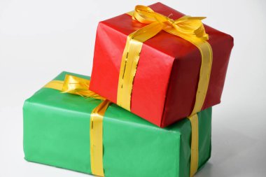 Kırmızı ve yeşil hediye kutusunun yakın plan fotoğrafı. Beyaz izole edilmiş arka planda altın sarısı bir kurdele var. Noel ve Yeni Yıl için hediyeler