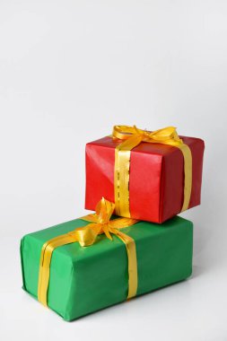 Kırmızı ve yeşil hediye kutusunun yakın plan fotoğrafı. Beyaz izole edilmiş arka planda altın sarısı bir kurdele var. Noel ve Yeni Yıl için hediyeler