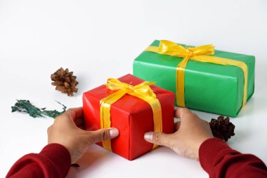 A closeup image of two hands holding a red and a green gift box against a clean white background. This festive photo embodies the spirit of Christmas and New Year celebrations clipart