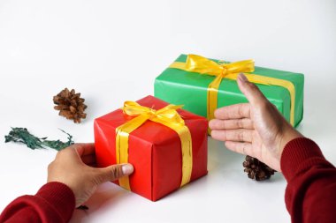 A closeup image of two hands holding a red and a green gift box against a clean white background. This festive photo embodies the spirit of Christmas and New Year celebrations clipart