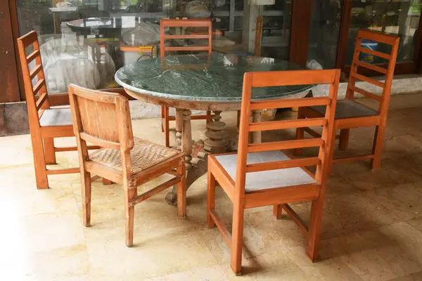 Örülmüş ahşap sırtı ve koltukları yuvarlak mermer bir masanın etrafında olan dört antika ahşap sandalye. Endonezya 'dan gelen Cava kültürel çalışmaları.
