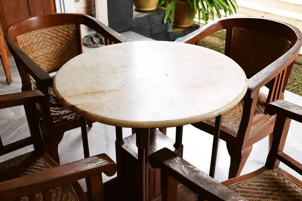 Örülmüş ahşap sırtı ve koltukları yuvarlak mermer bir masanın etrafında olan dört antika ahşap sandalye. Endonezya 'dan gelen Cava kültürel çalışmaları.