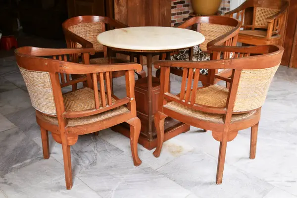 Örülmüş ahşap sırtı ve koltukları yuvarlak mermer bir masanın etrafında olan dört antika ahşap sandalye. Endonezya 'dan gelen Cava kültürel çalışmaları.