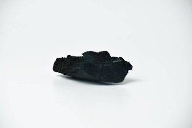Temiz beyaz bir zemin üzerine izole edilmiş siyah bir kömür parçası ürün gösterimi ya da tasarım elementleri için mükemmel..