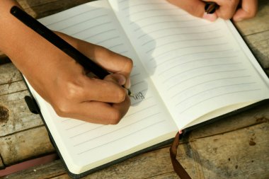 Bambu masasının üzerine doğal bir arka planı olan el yazısıyla yazılmış bir kitap. Doğa çalışmaları, geleneksel öğrenme ve Dünya Kitap Günü temaları için ideal.