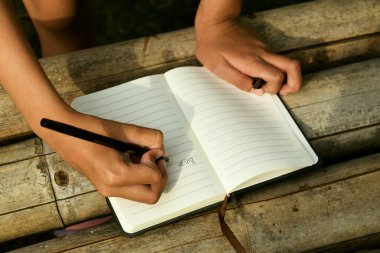 Bambu masasının üzerine doğal bir arka planı olan el yazısıyla yazılmış bir kitap. Doğa çalışmaları, geleneksel öğrenme ve Dünya Kitap Günü temaları için ideal.