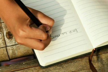 Bambu masasının üzerine doğal bir arka planı olan el yazısıyla yazılmış bir kitap. Doğa çalışmaları, geleneksel öğrenme ve Dünya Kitap Günü temaları için ideal.