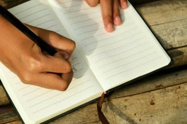 Bambu masasının üzerine doğal bir arka planı olan el yazısıyla yazılmış bir kitap. Doğa çalışmaları, geleneksel öğrenme ve Dünya Kitap Günü temaları için ideal.