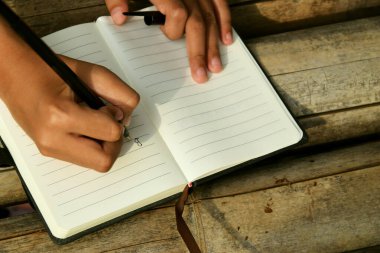 Bambu masasının üzerine doğal bir arka planı olan el yazısıyla yazılmış bir kitap. Doğa çalışmaları, geleneksel öğrenme ve Dünya Kitap Günü temaları için ideal.