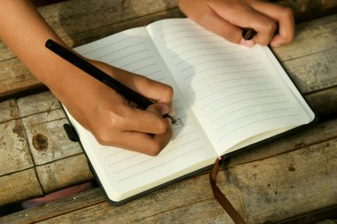 Bambu masasının üzerine doğal bir arka planı olan el yazısıyla yazılmış bir kitap. Doğa çalışmaları, geleneksel öğrenme ve Dünya Kitap Günü temaları için ideal.