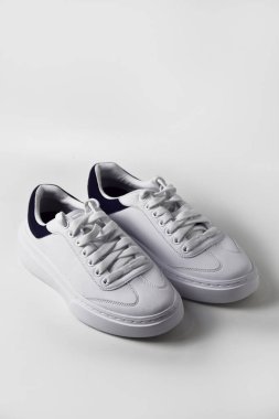 Temiz beyaz izole edilmiş arka planda minimalist beyaz spor ayakkabılar, parlak tasarım ve canlı detaylarla modern spor ayakkabıları sergileniyor..