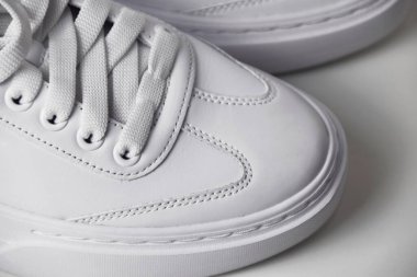 Temiz, izole edilmiş beyaz arka planda beyaz spor ayakkabıların yakın plan fotoğrafı, ayrıntılı dokular ve modern tasarım sergileniyor..