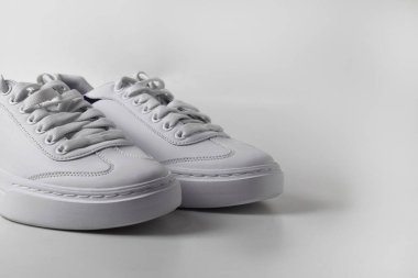 Temiz, izole edilmiş beyaz arka planda beyaz spor ayakkabıların yakın plan fotoğrafı, ayrıntılı dokular ve modern tasarım sergileniyor..
