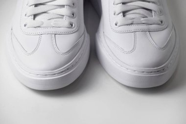 İzole edilmiş beyaz arka planda basit ve havalı beyaz spor ayakkabıların yakın plan fotoğrafı..