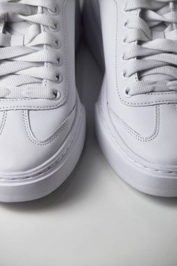 İzole edilmiş beyaz arka planda basit ve havalı beyaz spor ayakkabıların yakın plan fotoğrafı..